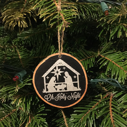 Bring the nativity scene to your tree with this beautiful sleek wood slice ornament. Crafted from birch wood. Measures 2.5-3.5 inches in diameter. Background painted in black, nativity scene and wording "Oh Holy Night" in silver. Jute rope hanger.