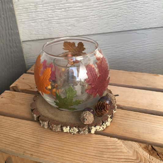 Base crafted from natural oak wood slice with bark.  Small votive cup inside round glass candleholder. Overall size is approx. 5 inch in diameter x 4 1/2 inch tall.  Leaves are decoupaged onto the glass. Berries, acorns & pine cone accents