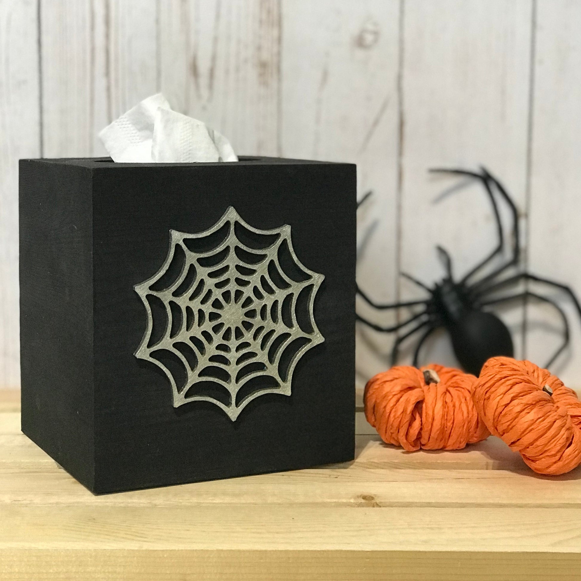 The box measures 5.75 inch x 5.25 inch and will fit any standard size facial tissue box (tissues not included). The silver metallic spiderweb wood cutout is on one side. The other 3 sides are painted in black. 