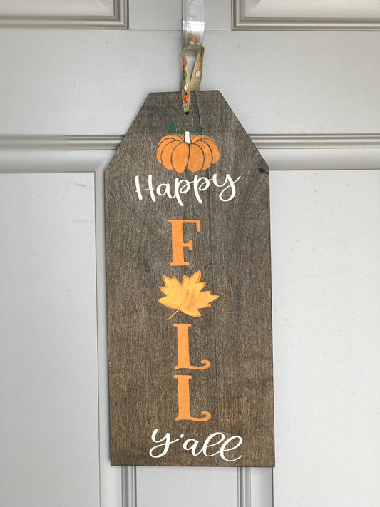 Hang this adorable "Happy Fall Y'all" wooden sign on your front door or display in your home to celebrate the fall time of year. Measures 17.75 in x 8 in x 1/4 in The sign is stained in a dark wood color with saying hand-painted on in orange and cream.  Ready to hang with fall ribbon. 