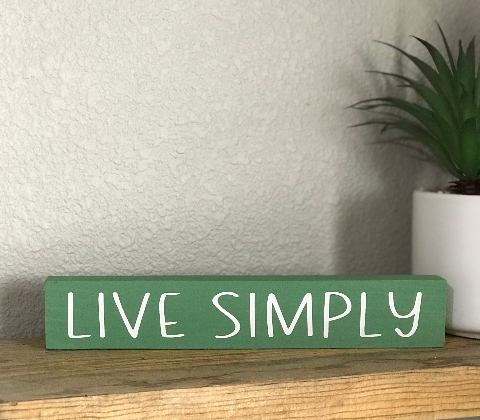 This cute, yet simple wood stick sign is 8 inch x 1 inch and is a perfect accent to your home decor. This sign is painted in a green color with the saying live simply in white.