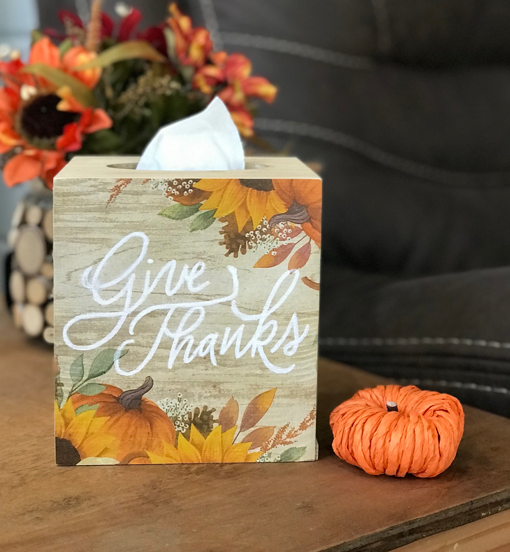 Crafted from wood Measures 5.75 inch x 5.25 inch Fits any standard size facial tissue box (not included). Pumpkin and sunflower graphic with the saying "Give Thanks" is on one side. Other 3 sides are painted in cream with some brown tones.  Slide bottom cover. 